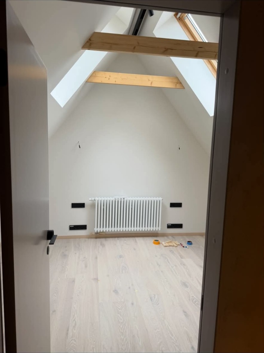 Finished attic bedroom with exposed timber beams and oak flooring